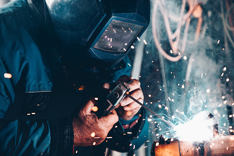 A welder in a welders mask shooting sparks